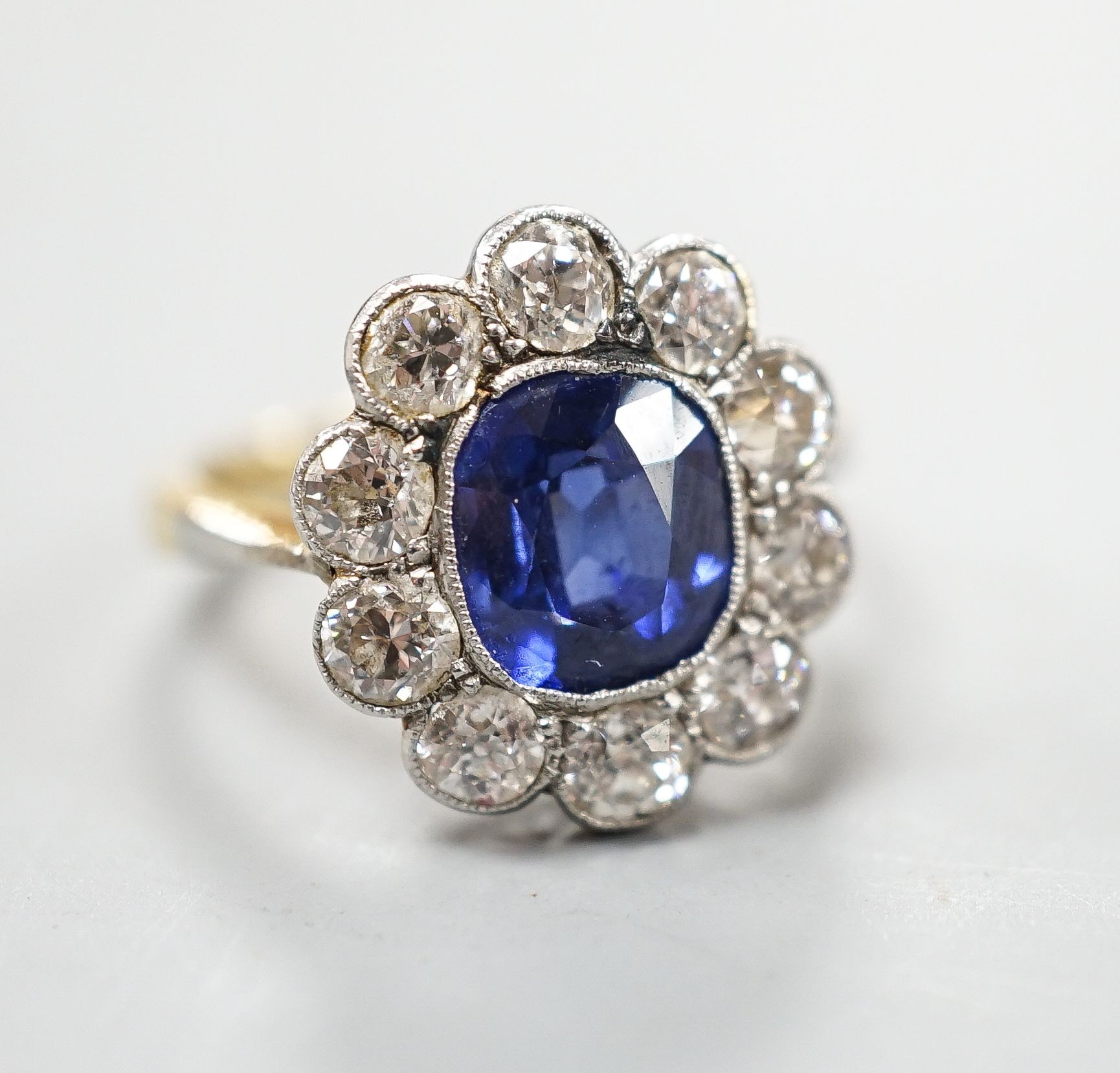 An 18ct gold and platinum, synthetic sapphire and diamond set oval cluster ring